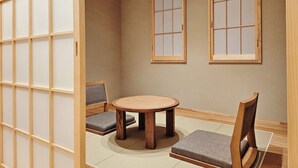 Una habitación japonesa tradicional con suelo de tatami, una mesa de madera baja y dos futones de tatami con cojines.