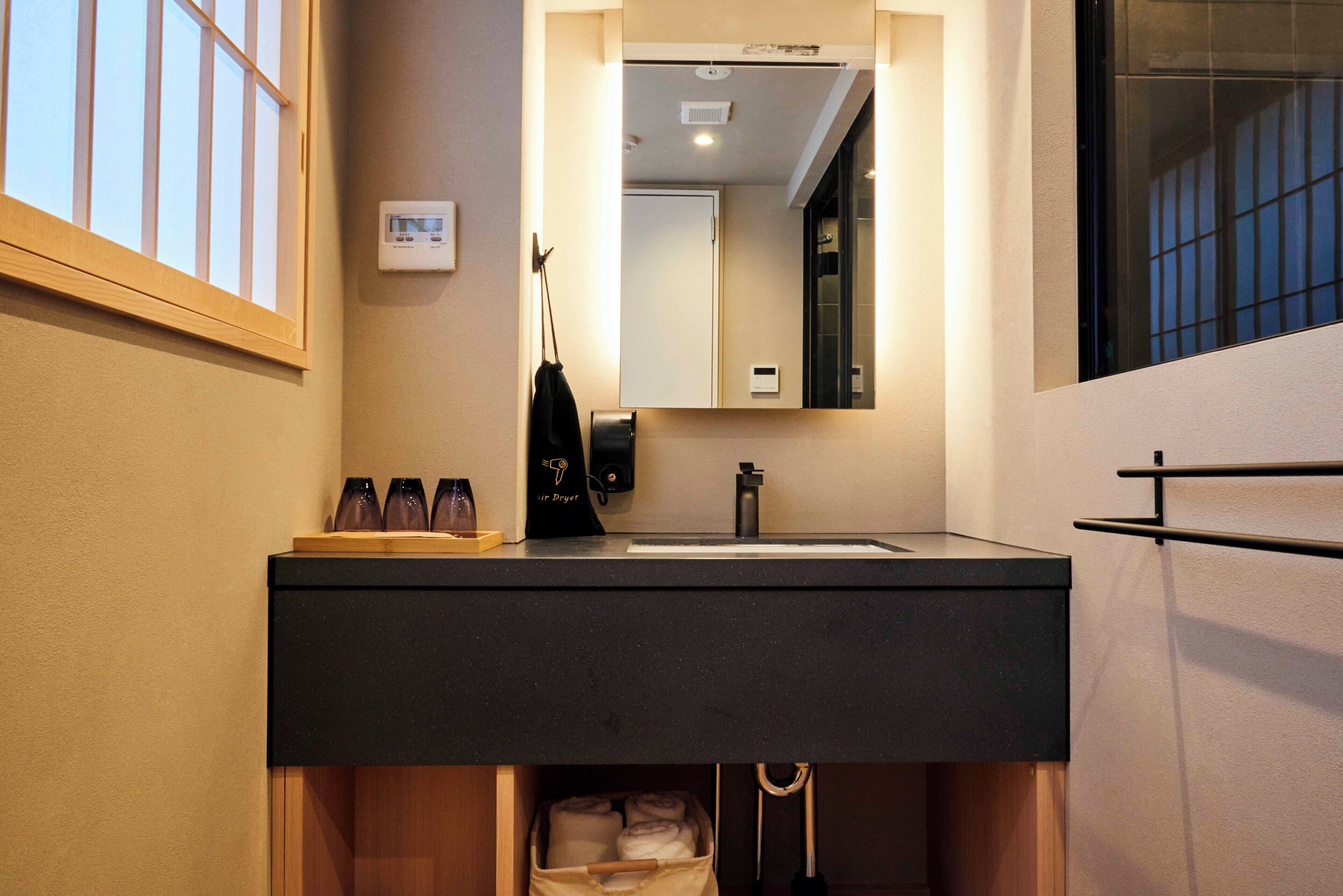 A modern bathroom with a black sink, a mirror, and a towel rack.