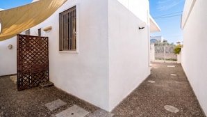 Un estrecho callejón con un edificio blanco, una puerta de madera y una cerca de metal.