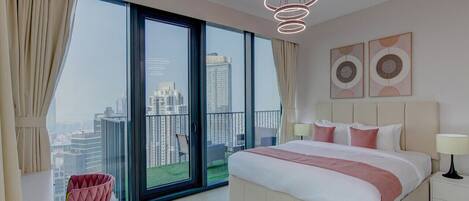 A modern bedroom with a large bed, a view of the city through floor-to-ceiling windows, and a balcony.