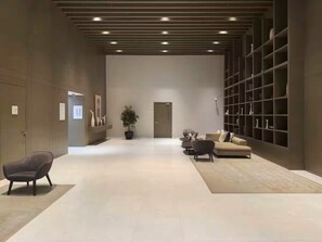 A spacious lobby with a modern design, featuring a sofa, chairs, a potted plant, and a bookshelf. - Vogue, Downtown Boulevard Heights near Burj Khalifa and Dubai Mall (Dubai)