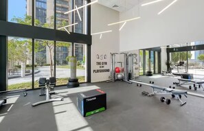 Une salle de sport moderne dotée de grandes fenêtres, d’équipements d’exercice et d’œuvres d’art murales inspirantes.