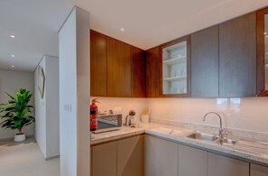 A modern kitchen with wooden cabinets, a stainless steel sink, and a microwave. - Vogue, Downtown Boulevard Heights near Burj Khalifa and Dubai Mall (Dubai)
