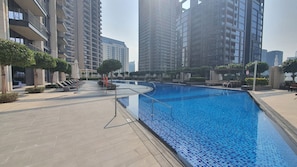A swimming pool with a tiled edge, surrounded by a paved walkway and trees. - Vogue, Downtown Boulevard Heights near Burj Khalifa and Dubai Mall (Dubai)