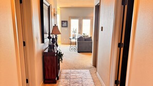 A hallway with a patterned rug, a lamp, and a sofa in the background.