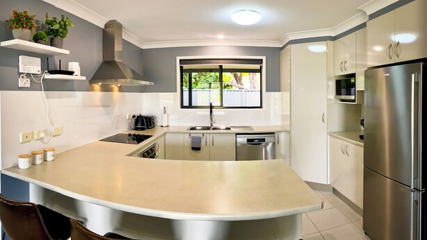 A modern kitchen with a central island, stainless steel appliances, and a window providing natural light.
