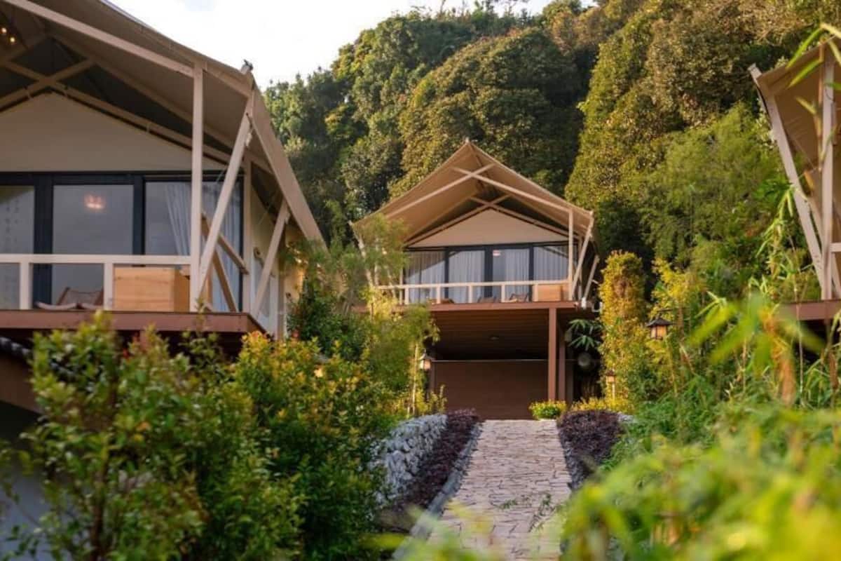 A resort with multiple bungalow-style buildings surrounded by lush greenery and a stone pathway leading to the entrance.