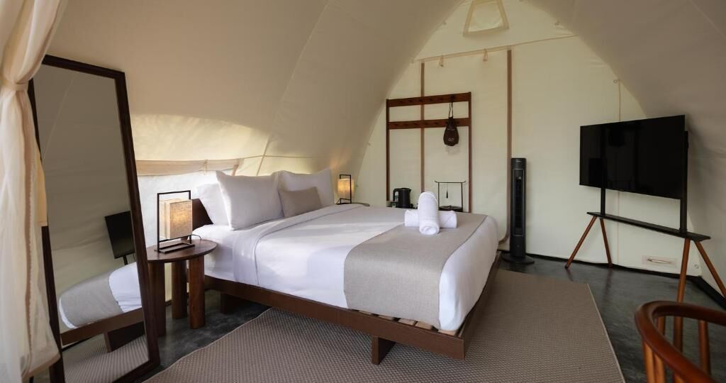 A spacious, well-lit room with a large bed, a television, and a mirror.