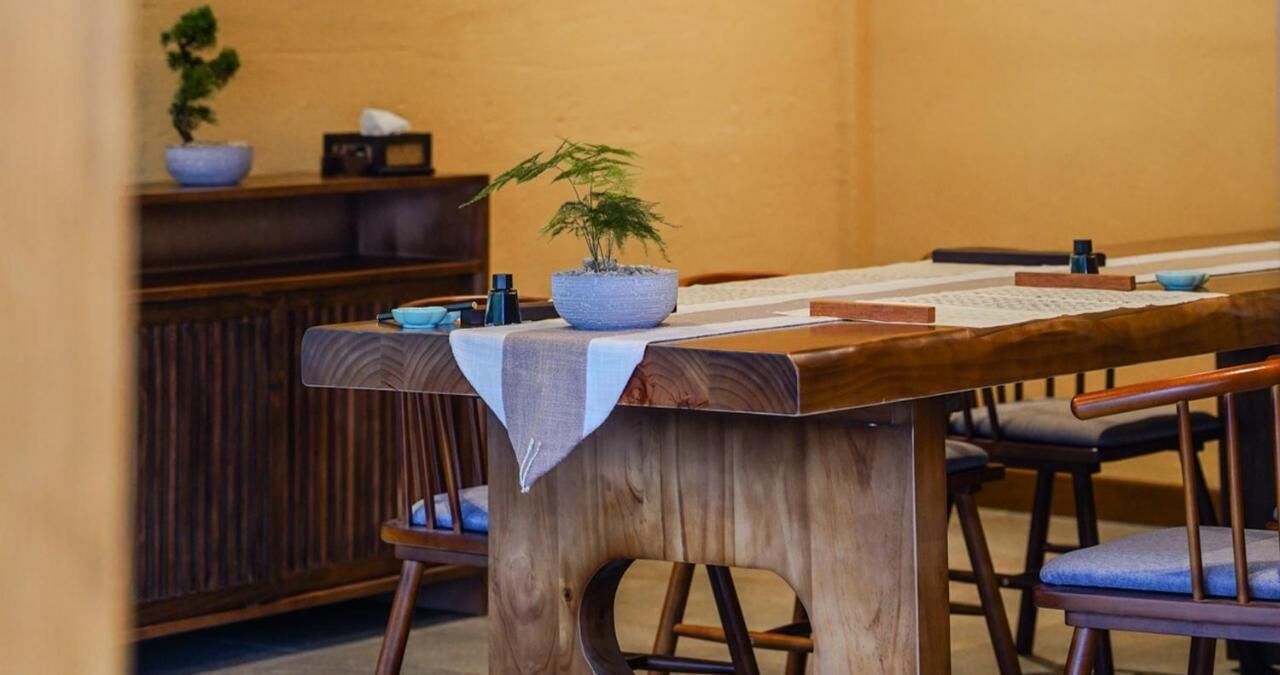 Una mesa de madera con un mantel blanco, una planta en maceta y un teclado.