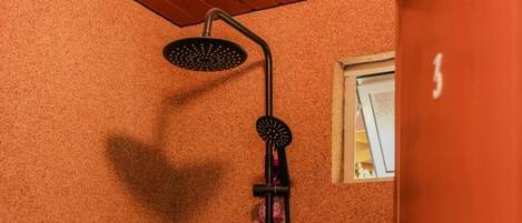 Una ducha con diseño curvo, una ventana pequeña y techo de madera.