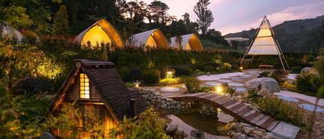 A series of dome-shaped accommodations surrounded by lush greenery, connected by a stone pathway.