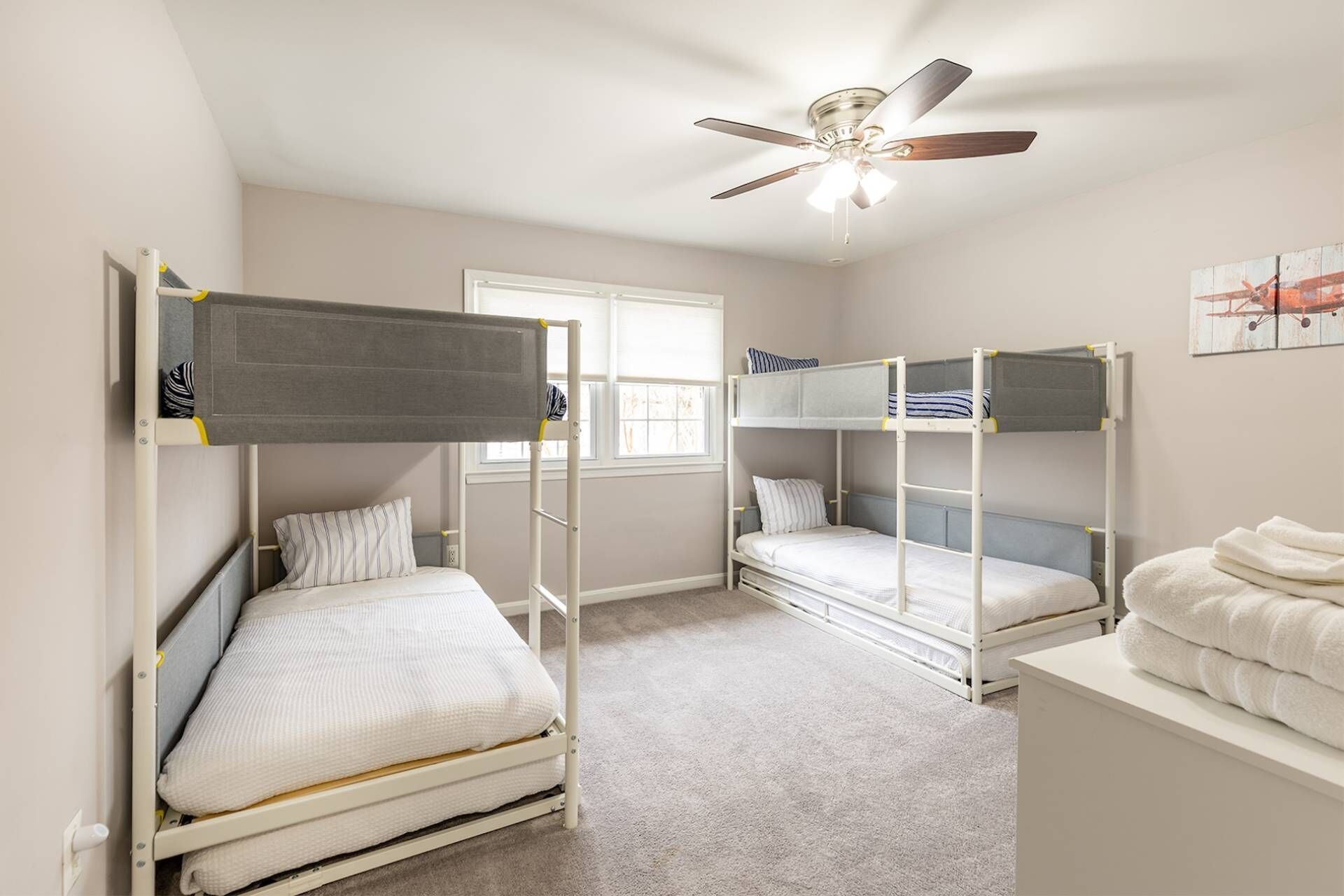 Une chambre avec des lits superposés, un ventilateur de plafond et une fenêtre.