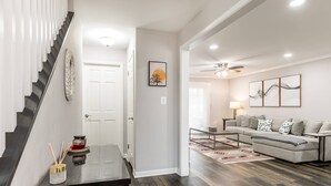 Un salon moderne avec un canapé gris, une table basse et un escalier avec une porte blanche.