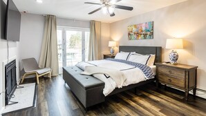 Une chambre à coucher comprenant un lit, des tables de chevet, un téléviseur et un ventilateur de plafond.
