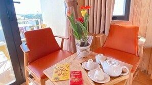 A wooden table with two orange chairs, a small potted plant with flowers, and a tray with teacups and a teapot. - La Maison Dalat (Lang Biang - Da Lat)