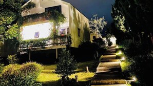 A modern building with a sloped roof, surrounded by greenery and a well-lit pathway leading to the entrance. - La Maison Dalat (Lang Biang - Da Lat)