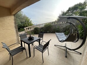 Relax in a tranquil outdoor space with a hammock, table, and chairs, surrounded by lush greenery and a stone staircase.