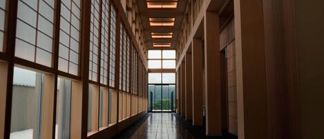 A long, narrow hallway with large windows on one side and a door at the end.