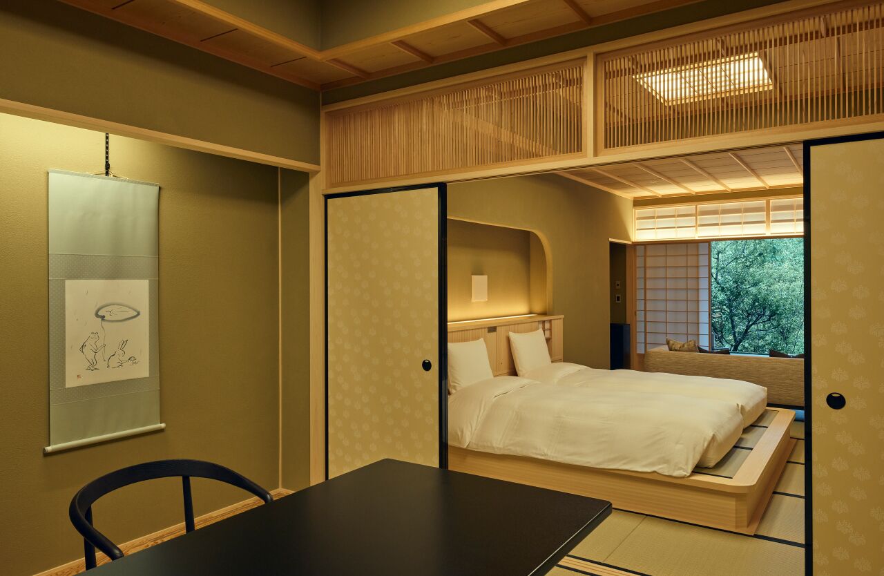 A traditional Japanese-style room with tatami flooring, a low bed, and a sliding shoji screen door.