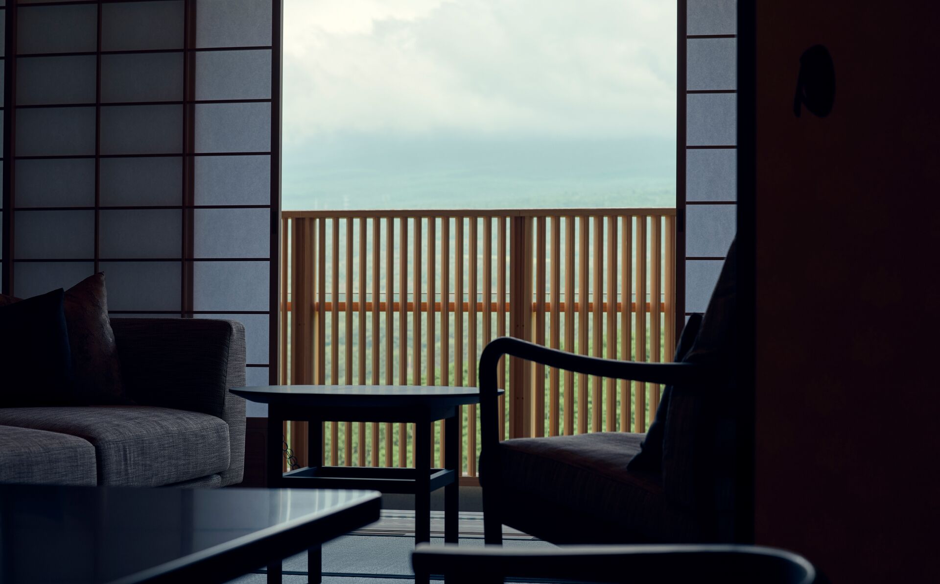 Une pièce avec vue sur une terrasse en bois et un ciel nuageux.