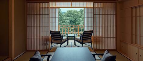 A traditional Japanese room with tatami flooring, a low table, two chairs, and shoji screens.