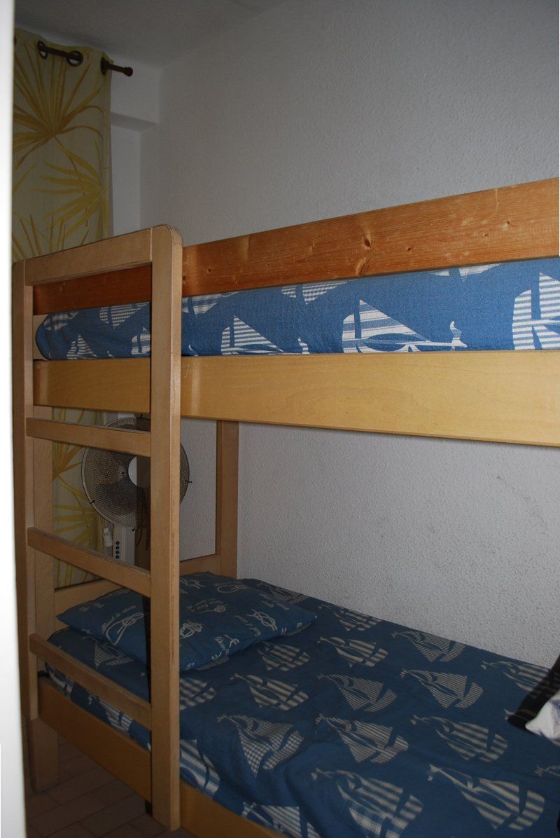 A bunk bed with a blue patterned mattress and a wooden frame.