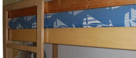 A bunk bed with a blue patterned mattress and a wooden frame.