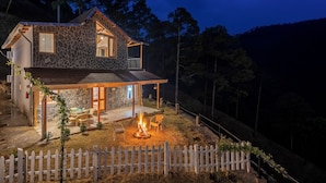 Una casa de piedra con un hogar, asientos al aire libre y una cerca blanca de piquete.
