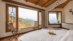 Un dormitorio con una cama grande, dos sillas, un aparador y una ventana con vistas al campo.