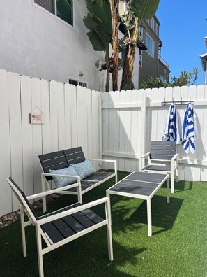 A white picket fence with a bench and a table, a welcome sign, and a flag.