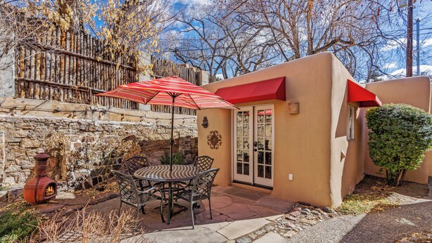 A patio with a table and chairs, a red umbrella, and a stone stove.
