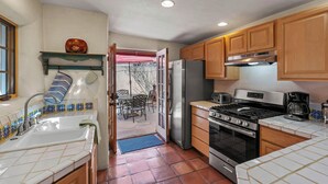 A kitchen with a sink, stove, refrigerator, and wooden cabinets.