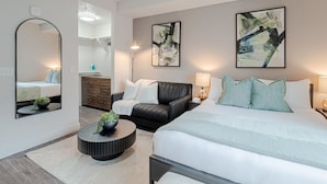 Ein modernes Schlafzimmer mit einem großen Bett, einer schwarzen Ledersofa, einem runden Couchtisch und zwei Wandlampen.