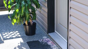 Ein Haus mit schwarzem Eingang, einem Blumentopf und einer Fußmatte.