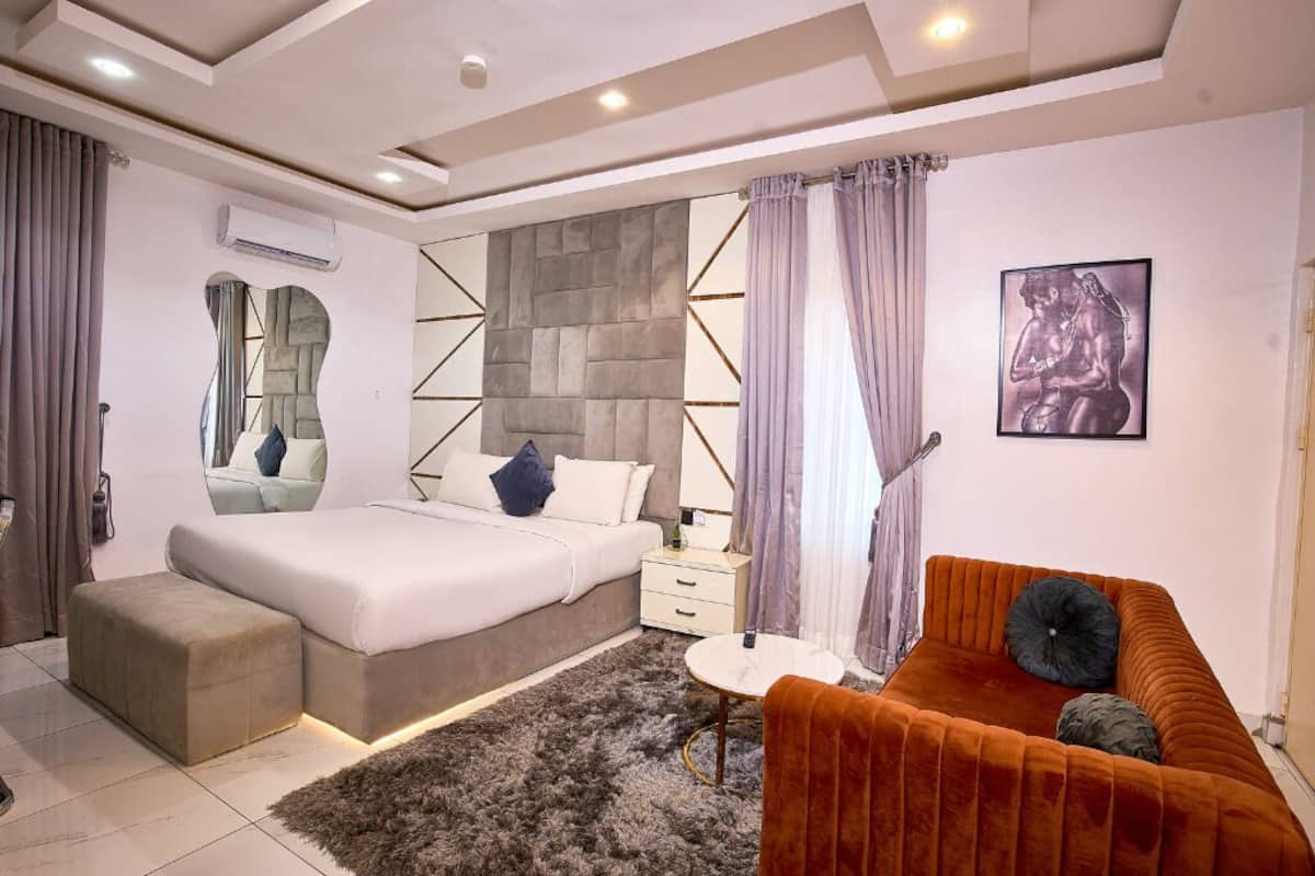 Une chambre à coucher moderne avec un lit, un canapé, une petite table et un miroir décoratif.