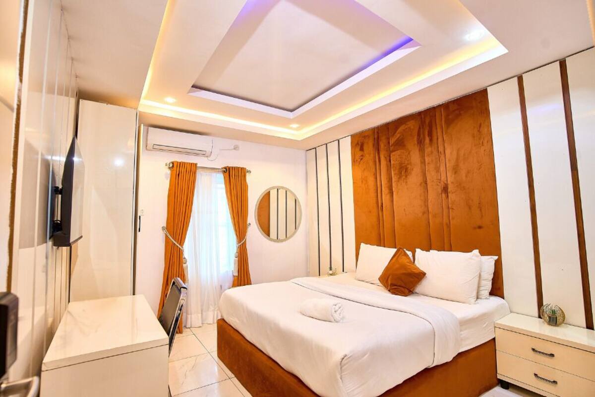 Une chambre d’hôtel moderne avec un grand lit, une table de chevet, un miroir et une armoire.
