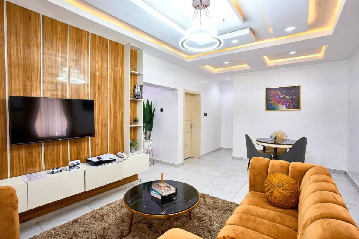 Un salon moderne doté d’un téléviseur à écran plat, d’un canapé, d’une table basse et d’un coin repas avec une petite table et des chaises.