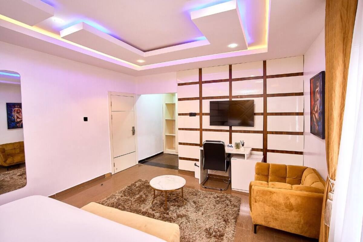 Un salon moderne comprenant un canapé, une table basse, un téléviseur fixé au mur et un bureau avec une chaise.