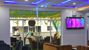 A modern restaurant interior with blue neon lighting, comfortable seating, and a TV screen on the wall. - Libertini Hotel and Apartments (Lekki)