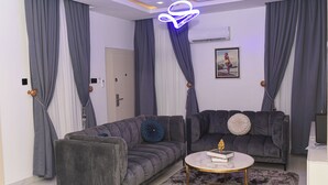 A modern living room with two grey sofas, a round coffee table, and a fluffy rug. - Libertini Hotel and Apartments (Lekki)