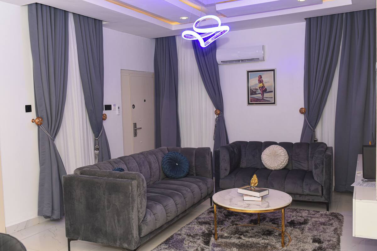 Un salon moderne avec deux canapés gris, une table basse ronde et un tapis moelleux.