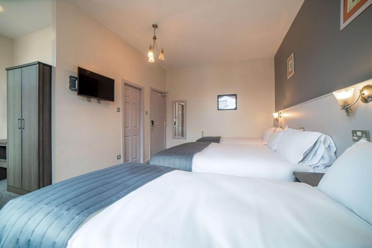 A hotel room with two beds, a television, a wardrobe, and a door.