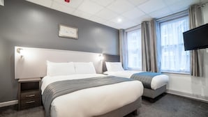 A hotel room with two beds, a flat-screen TV, a window with curtains, and a framed picture on the wall. - Gresham Hotel Blackpool (Blackpool)