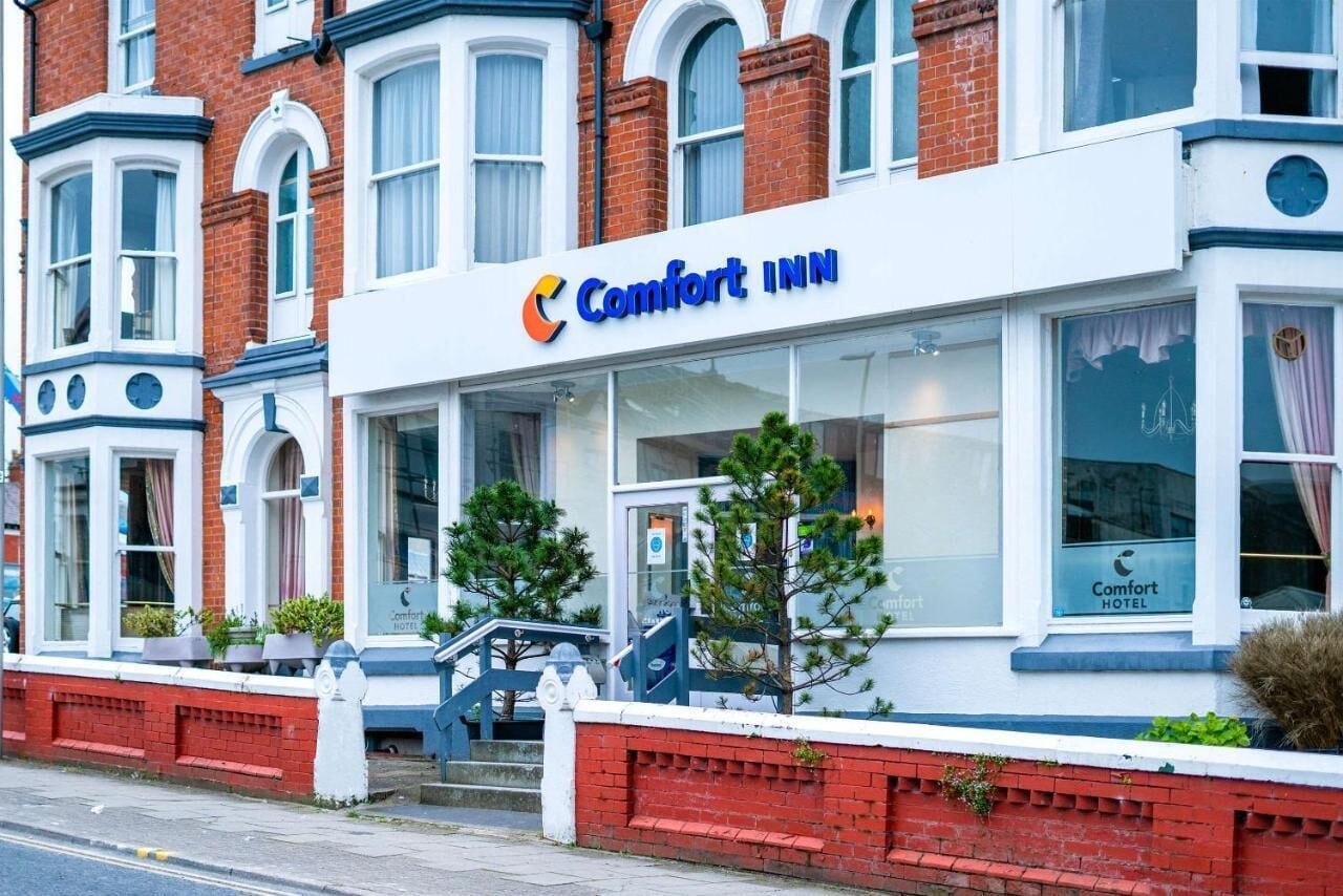 A Comfort Inn hotel with a white facade, large windows, and a visible entrance.