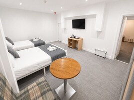 Een hotelkamer met twee bedden, een televisie, een bureau en een ronde tafel.