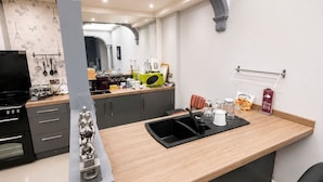 A modern kitchen with a central island, dark cabinetry, and a visible stove. - Gresham Hotel Blackpool (Blackpool)
