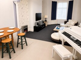 Een woonkamer met een open haard, een televisie, een piano en een bank.