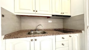 Cocina con armarios blancos, pileta de acero inoxidable y encimera de granito.