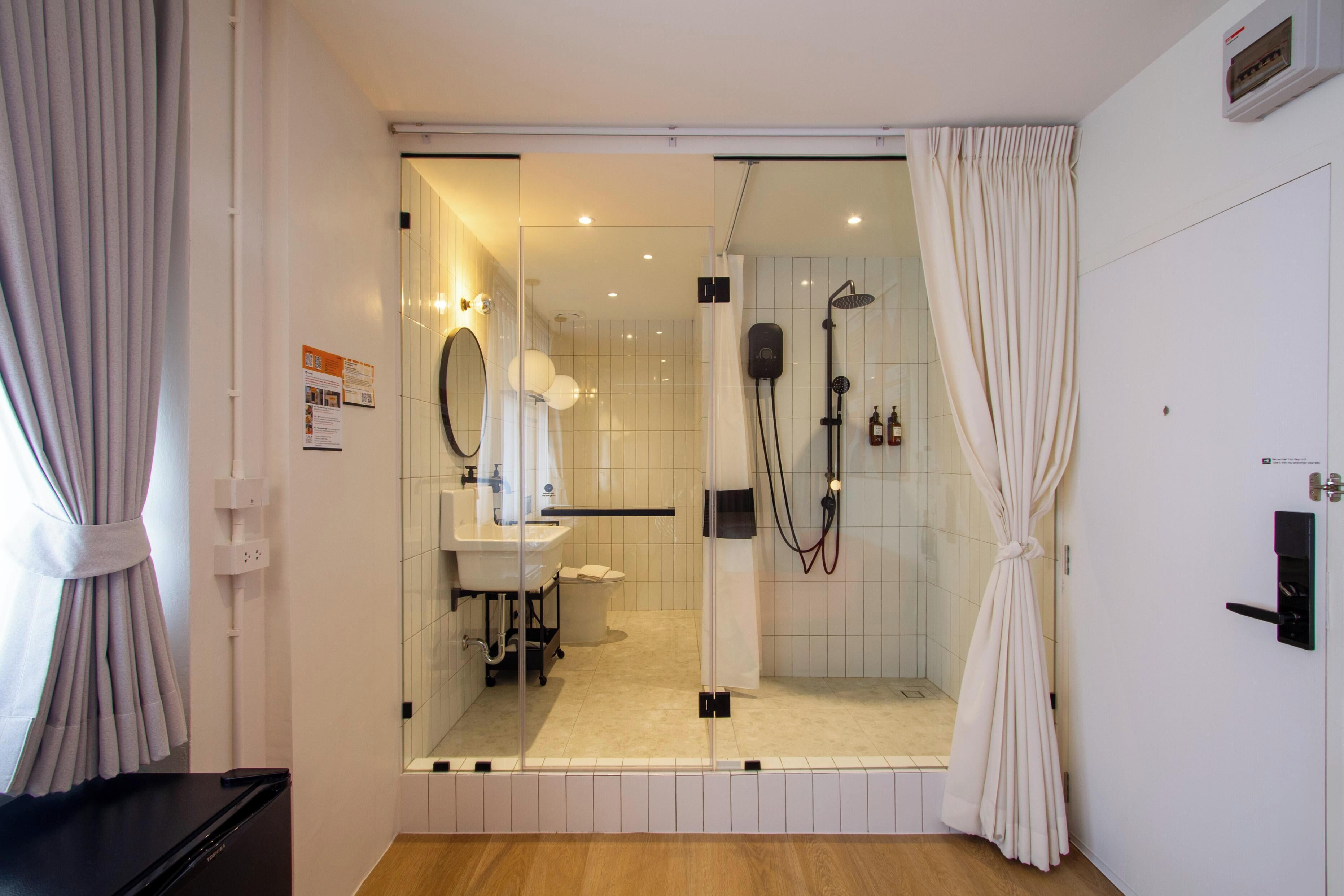 A modern bathroom with a glass shower enclosure, a sink, and a mirror.