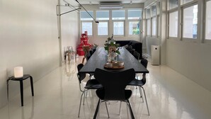 Een moderne vergaderruimte met een lange tafel, zwarte stoelen en een witte vloer.